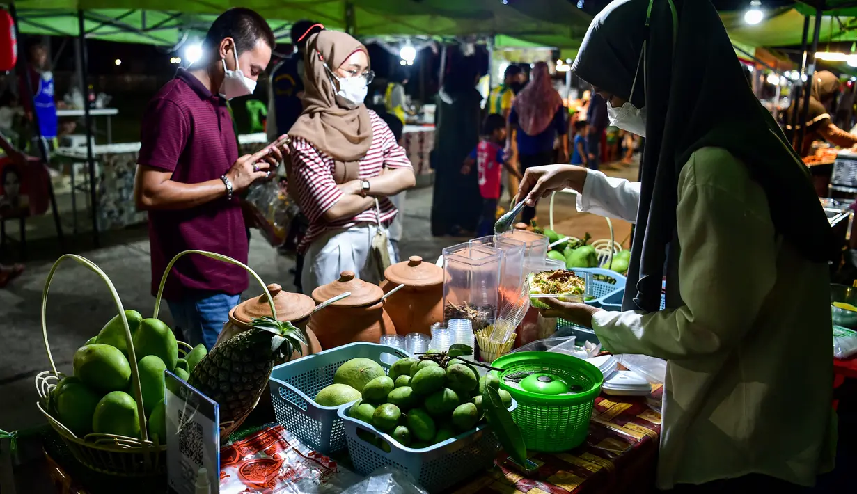 <p>Penjual membuat minuman untuk pembeli  selama bulan suci Ramadhan di pasar malam di provinsi Narathiwat, Thailand selatan (21/4/2022). Penjual makanan jalanan mendirikan kios mereka untuk menjual makanan kepada umat Muslim untuk berbuka puasa. (AFP/Madaree Tohlala)</p>