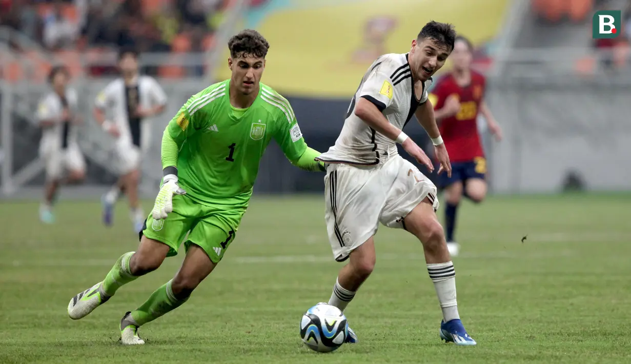 Pemain Timnas Jerman U-17, Bilal Yalcinkaya (kanan) mendapatkan gangguan dari kiper Timnas Spanyol U-17, Raul Jimenez, saat pertandingan perempat final Piala Dunia U-17 2023 yang berlangsung di Jakarta International Stadium, Jumat (24/11/2023). (Bola.com/Arief Bagus)