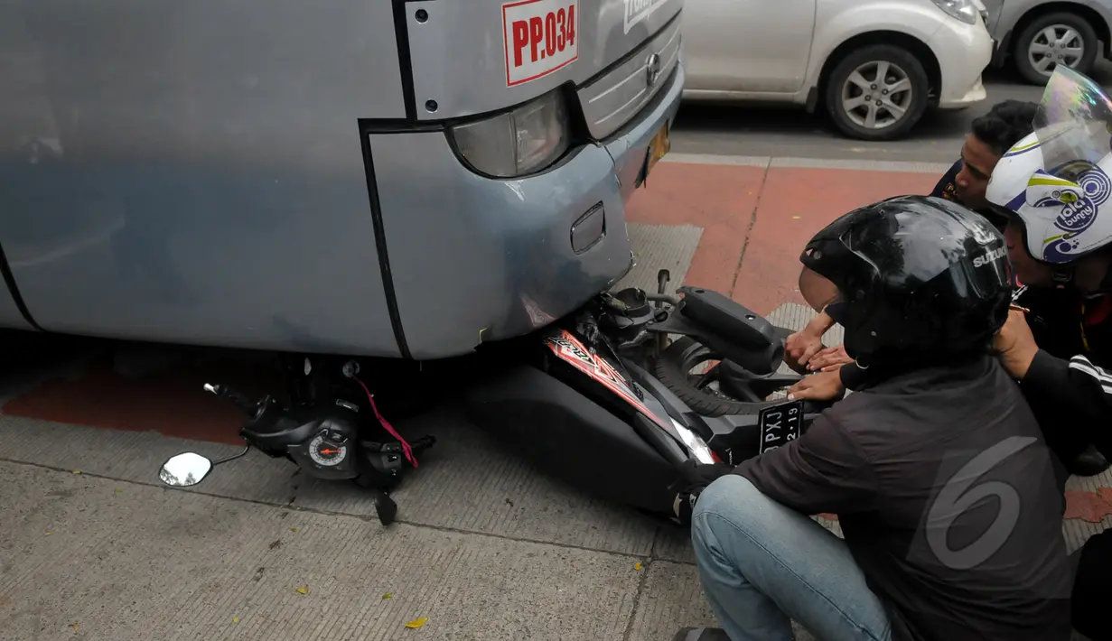 Sejumlah warga melihat kondisi sepeda motor yang tertabrak Bus Transjakarta di kawasan permata hijau, Jakarta, Jumat (27/3/2015). Sejumlah warga sedang melakukan evakuasi speda motor yang berada di dalam bus transjakarta. (Liputan6.com/Johan Tallo)