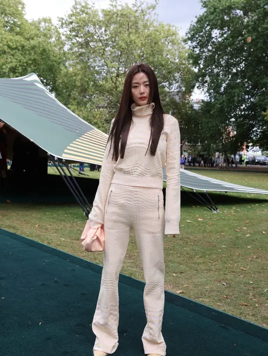 Berbeda dari Bright, Jun Ji Hyun tampil lebih kalem dengan setelan turtleneck warna broken white yang dipadu clutch warna coral. [Dok/Burberry]