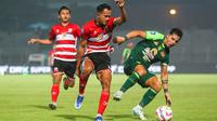 Pemain Madura United, Koko Ari Araya, berduel dengan gelandang serang Persebaya Surabaya, Bruno Moreira, pada lanjutan BRI Liga 1 2024/2025, Senin (2/12/2024) malam WIB. (Bola.com/Aditya Wany)