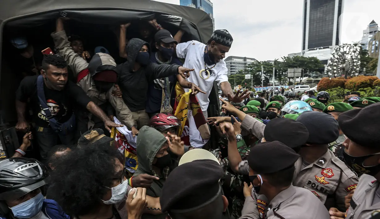 Polisi dan tentara menjaga masyarakat Papua yang memperingati Operasi Trikora 19 Desember 1961 di Patung Kuda, Jakarta, Sabtu (19/12/2020). Massa juga menuntut penghentian rasisme dan politik rasial. (Liputan6.com/Johan Tallo)