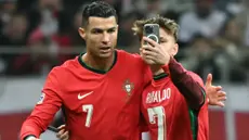 Seorang penyusup lapangan melakukan swafoto dengan pemain Portugal, Cristiano Ronaldo (kiri) saat laga lanjutan EUFA Nations League Polandia di National Stadium, Warsawa, Polandia, Minggu (13/10/2024) WIB. (AFP/Sergei Gapon)