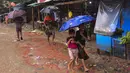 Dua anak pengungsi Rohingya berjalan menggunakan payung saat hujan di kamp pengungsi Kutupalong, Ukhia (12/9/2019). Kamp ini didirikan secara tidak resmi pada tahun 1991, setelah ribuan orang Rohingya melarikan diri dari Operasi Pyi Thaya yang dilancarkan militer Burma. (AFP Photo/Munir Uz Zaman)