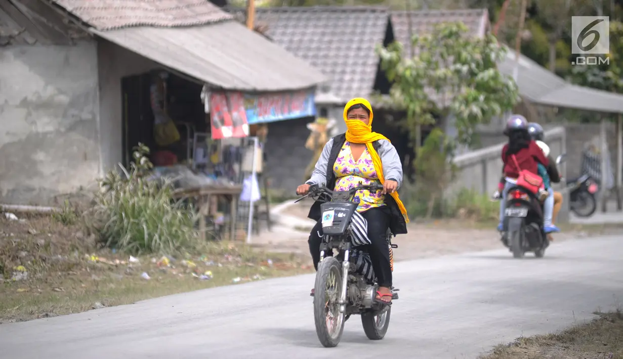 Pengendara sepeda motor mengenakan masker saat melintas di Desa Pempatan, Karangasem, Bali, Sabtu (30/6). Abu vulkanik erupsi Gunung Agung menyelimuti rumah dan kebun warga di sisi barat laut Gunung Agung. (Merdeka.com/Arie Basuki)
