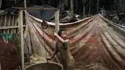 Akses makan yang terbatas sampai kebersihan yang sulit dijaga bisa memengaruhi kondisi fisik dan kesehatan anak. Tampak dalam foto, Baiti Arafah mengambil seember air dari sumur untuk membersihkan diri setelah bermain di genangan lumpur di Babo, Aceh Tamiang, pada Senin 15 Desember 2025. (Yasuyoshi Chiba/AFP)