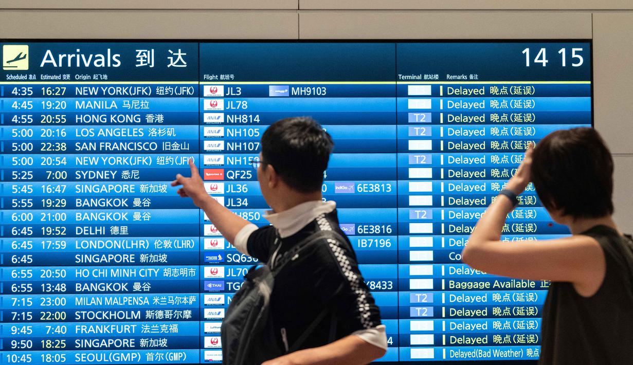 Penumpang melihat papan informasi penerbangan kedatangan di Terminal Internasional Bandara Haneda setelah penerbangan dibatalkan atau ditunda karena badai tropis Jangmi di Tokyo, Jepang, Rabu 3 Juni 2026. (Andrew CAALLERO-REYNOLDS/AFP)
