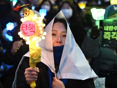 Salah satu pengunjuk rasa melambaikan tongkat cahaya (light stick) saat mereka mengambil bagian dalam protes yang menyerukan penggulingan Presiden Korea Selatan Yoon Suk Yeol di sebuah jalan dekat Majelis Nasional di Seoul pada tanggal 13 Desember 2024. (Jung Yeon-je/AFP)