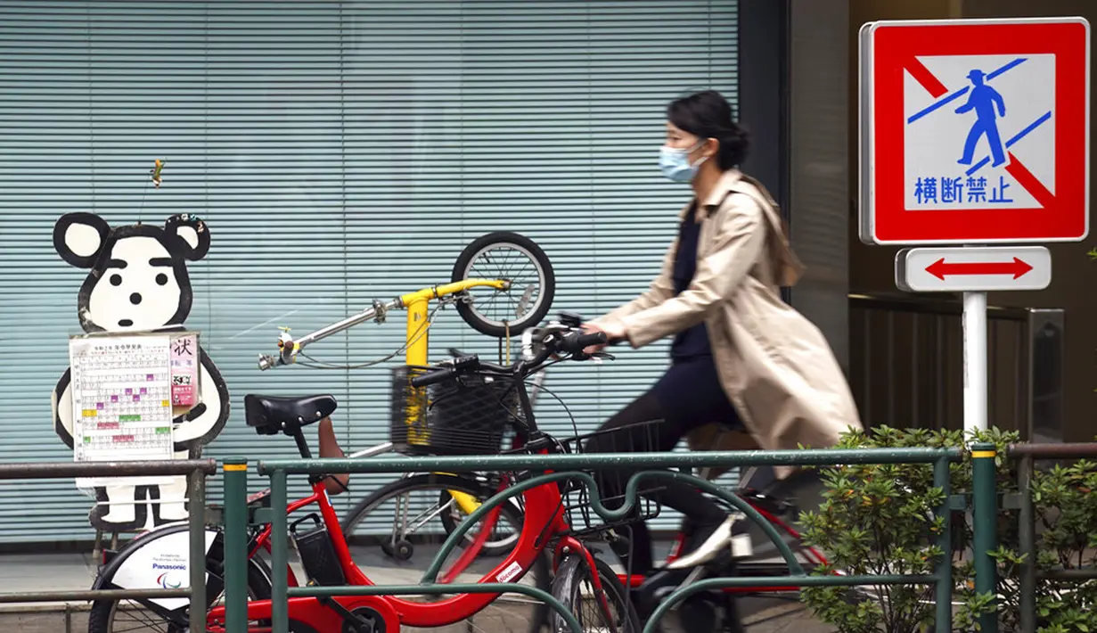 Seorang wanita yang mengenakan masker untuk membantu mengekang penyebaran COVID-19 mengendarai sepeda di Tokyo, Jepang, Senin (2/11/2020). Tokyo mengonfirmasi lebih dari 80 kasus baru COVID-19 pada 2 Oktober 2020. (AP Photo/Eugene Hoshiko)