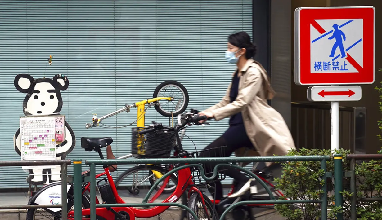 Seorang wanita yang mengenakan masker untuk membantu mengekang penyebaran COVID-19 mengendarai sepeda di Tokyo, Jepang, Senin (2/11/2020). Tokyo mengonfirmasi lebih dari 80 kasus baru COVID-19 pada 2 Oktober 2020. (AP Photo/Eugene Hoshiko)