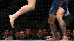 Conor McGregor (kiri) menghantamkan lututnya ke wajah Donald 'Cowboy' Cerrone pada pertarungan kelas welter UFC 246 di T-Mobile Arena, Las Vegas, Amerika Sertikat, Sabtu (18/1/2020). McGregor mengalahkan Cowboy pada detik ke-40. (Steve Marcus/Getty Images/AFP)