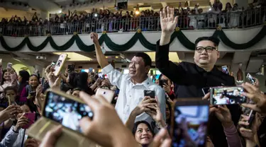 Peniru Presiden Filipina Rodrigo Duterte, Cresencio Extreme (tengah) dan peniru pemimpin Korea Utara Kim Jong Un, Howard X melambaikan tangan ketika menghadiri kebaktian gereja di pusat Hong Kong pada 3 Februari 2019. (ISAAC LAWRENCE/AFP)