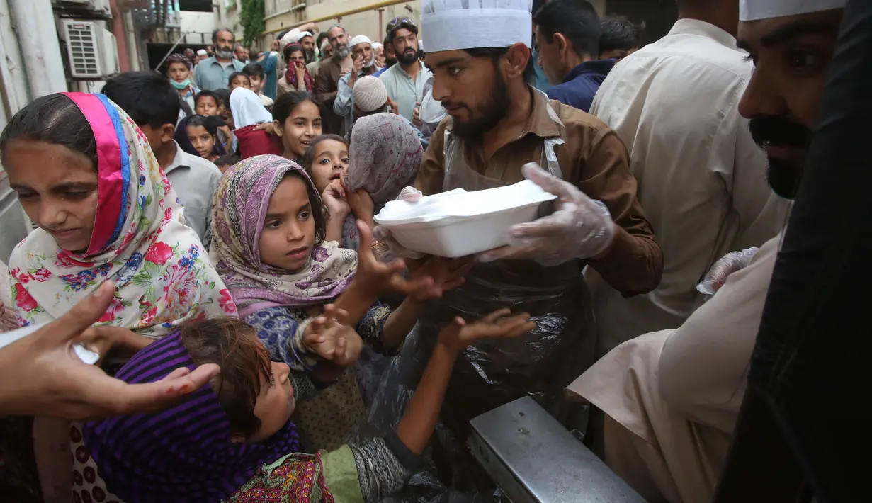 Relawan mendistribusikan kotak makanan untuk orang-orang yang berbuka puasa bersama selama bulan suci Ramadan di Peshawar, Pakistan, Senin (11/5/2020). Warga berbuka puasa bersama setelah pemerintah melonggarkan lockdown terkait pandemi virus corona COVID-19. (AP Photo/ Muhammad Sajjad)