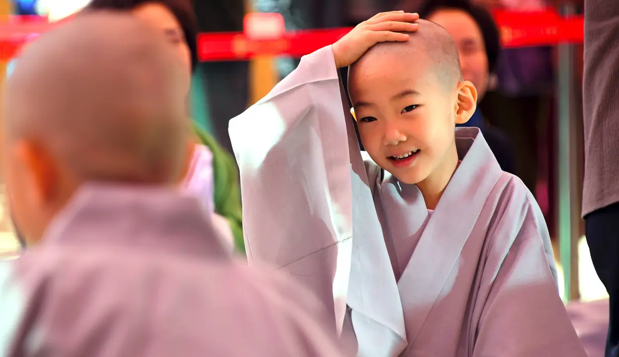 Reaksi seorang anak usai dicukur saat upacara 'Anak-anak Menjadi Buddha Monks', di kuil Jogye, Seoul, Rabu (19/4). Setelah upacara anak-anak akan tinggal di kuil selama dua minggu untuk mengikuti perayaan ulang tahun Buddha. (AFP PHOTO / JUNG Yeon-Je)