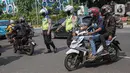 Petugas kepolisian lalu lintas memberhentikan pengendara motor saat Operasi Zebra Jaya 2020 di kawasan Cawang, Jakarta, Senin (26/10/2020). Operasi Zebra Jaya dilaksanakan pada 26 Oktober-8 November 2020 untuk menekan jumlah pelanggaran lalu lintas. (Liputan6.com/Faizal Fanani)