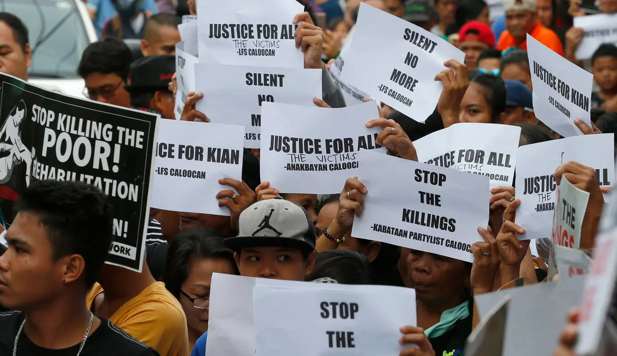 Para pemrotes membawa poster dan spanduk saat mengiringi pemakaman jenazah Kian Loyd delos Santos di Caloocan, Filipina (26/8). Mereka yang ikut mengiringi pemakaman menggunakan kaos putih bertuliskan 'Justice for Kian.' (AP Photo/Bullit Marquez)
