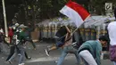 Massa melempar batu ke arah polisi yang membentuk barikade dengan tameng di sekitaran Gedung DPR RI, Jakarta, Senin (30/9/2019). Kericuhan pecah lantaran massa yang kebayakan terdiri dari pelajar tersebut berusaha masuk ke area depan DPR. (Liputan6.com/Angga Yuniar)
