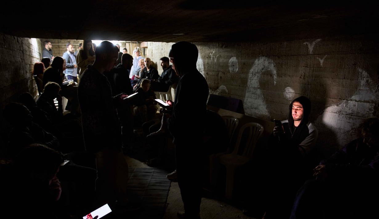 Warga berlindung di tempat perlindungan bom saat sirene serangan udara memperingatkan akan datangnya serangan rudal Iran di Ramat Gan, Israel, Rabu, 25 Maret 2026. (AP Photo/Oded Balilty)