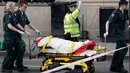 Petugas mengevakuasi korban terluka dalam serangan teror di dekat gedung Parlemen Inggris, London, Rabu (22/3). Pelaku penyerangan menembaki sejumlah pejalan kaki sambil mengemudikan mobilnya di jembatan Westminster. (AP Photo/Matt Dunham)