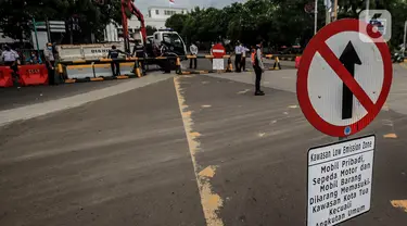 Petugas Dinas Perhubungan DKI Jakarta menurunkan beton barrier saat penutupan akses jalan menuju kawasan Kota Tua, Jumat (18/12/2020). Pemprov DKI membatasi moda transportasi melintasi kawasan wisata Kota Tua seiring penerapan kawasan rendah emisi atau Low Emission Zone. (Liputan6.com/Johan Tallo)