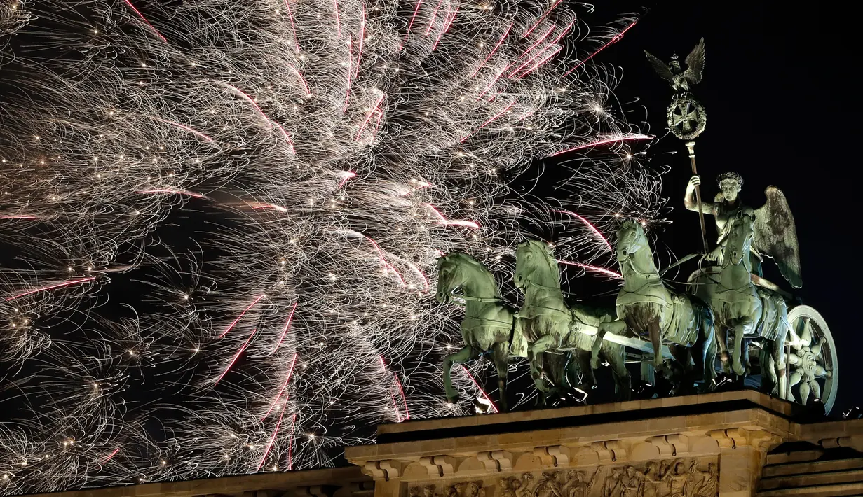 Pesta kembang api menyemarakkan perayaan malam Tahun Baru 2019 di atas Gerbang Brandenburg, Berlin, Jerman, Selasa (1/1). (AP Photo/Michael Sohn)