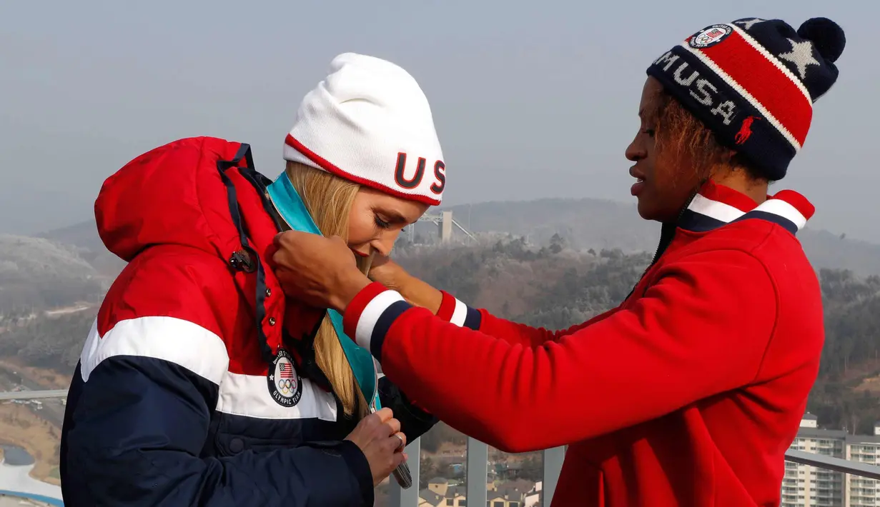 Atlet kereta luncur wanita AS Lauren Gibbs mengalungi medali perak kepada putri Presiden AS, Ivanka Trump selama kejuaraan Olimpiade Musim Dingin Pyeongchang 2018 di depan menara lompat ski di Pyeongchang (25/2). (AFP Photo/Pool/Eric Gaillard)