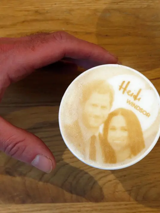 Seorang pria memegang kopi Capuccino dengan dengan latte art gambar Pangeran Harry dan Meghan Markle di kedai kopi, Windsor, 15 Mei 2018. Inggris sedang mempersiapkan pernikahan Harry dan Meghan pada 19 Mei mendatang di Windsor Castle. (AP/Frank Augstein)