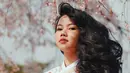 Yura Yunita tampak begitu menawan saat mengenakan hanbok warna putih. Latar belakang bunga sakura semakin menyempurnakan kecantikan dari Yura. (Foto: instagram.com/yurayunita)