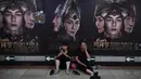 Seorang pria dan wanita beristirahat di depan poster film Asura di stasiun kereta bawah tanah di Beijing, Selasa (17/7). Film fantasi ini dilaporkan menelan biaya produksi sebesar 750 juta yuan (sekitar Rp1,6 triliun). (AFP/GREG BAKER)