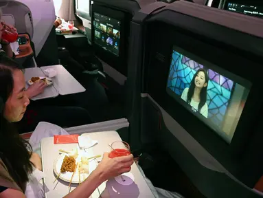 Pengunjung menonton film sembari menikmati makanan di kelas bisnis selama makan siang perdana di Restaurant A380 @Changi di atas pesawat Airbus A380, di Bandara Internasional Changi, 24 Oktober 2020. Singapore Airlines mengubah salah satu pesawatnya menjadi sebuah restoran mewah. (ROSLAN RAHMAN/AFP)