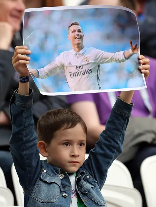 Seorang anak menunjukan poster bergambar bintang Real Madrid, Cristiano Ronaldo, sebelum laga Grup A Piala Konfederasi antara Portugal melawan Meksiko di Stadion Kazan Arena, Kazan, Minggu (18/6/2017). (EPA/Tolga Bozoglu)