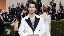 Hadir di Met Gala 2022, Joe Jonas pun tampil dengan suit putih berpadu hitam sesuai dengan celananya. Suit tersebut pun memiliki train lace putih. (@joejonas)