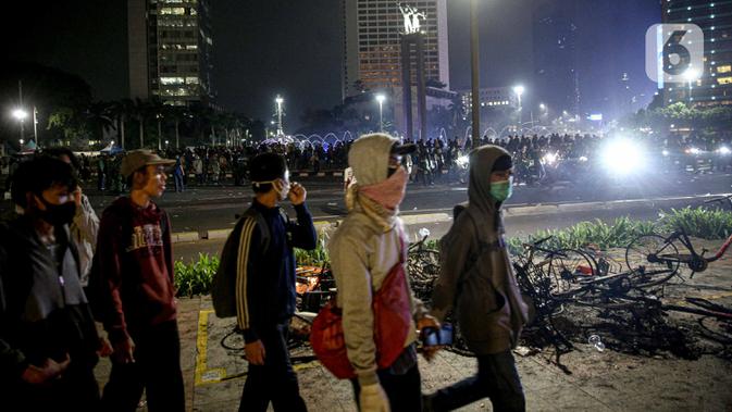 Sejumlah orang berjalan usai demonstrasi yang berujung anarkis di kawasan Bundaran HI, Jakarta, Kamis (8/10/2020). Massa membakar sejumlah barang saat demonstrasi menolak pengesahan UU Cipta Kerja. (Liputan6.com/Faizal Fanani)