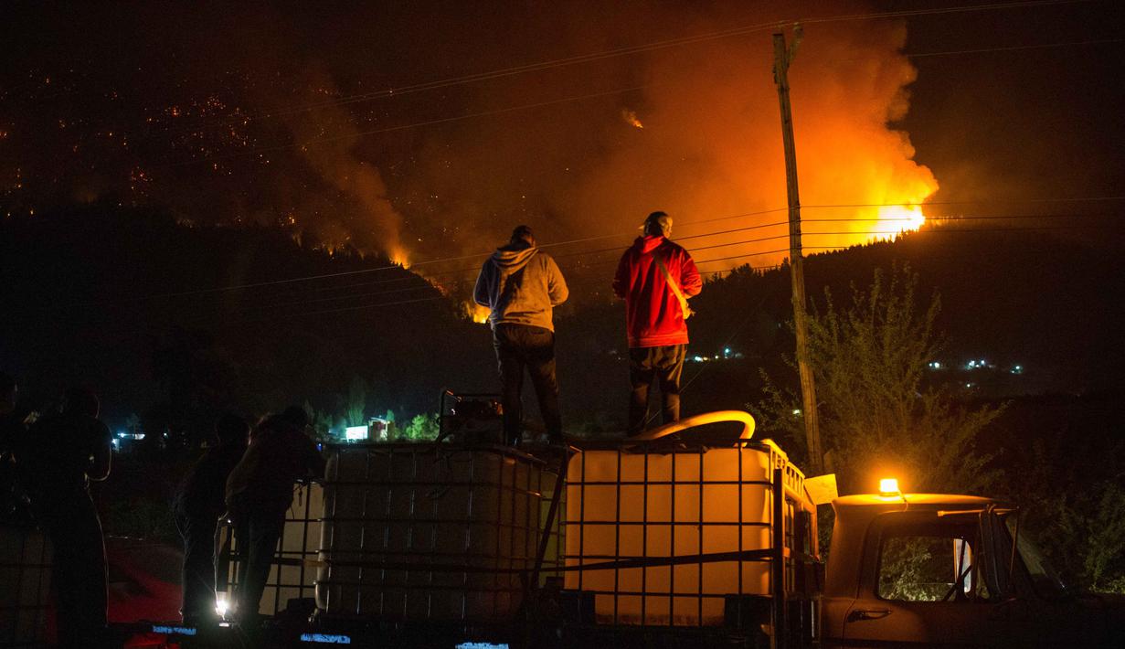 Orang-orang menunggu di atas truk air saat kebakaran hutan berkobar di Gunung Pirque, El Hoyo, wilayah Patagonia provinsi Chubut, Argentina pada 7 Januari 2026. Ribuan hektar hutan di Gunung Pirque, El Hoyo, wilayah Patagonia provinsi Chubut, Argentina, hancur akibat kebakaran yang terjadi sejak 6 Januari 2026. (Martin LEVICOY/AFP)