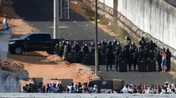 Seorang tahanan berbicara dengan polisi setelah bentrokan di penjara Alcacuz, Natal, Rio Grande do Norte, Brasil, (16/1). Polisi harus menggunakan peluru karet untuk membubarkan bentrokan antar geng tersebut. (AFP Photo/Andressa Anholette)