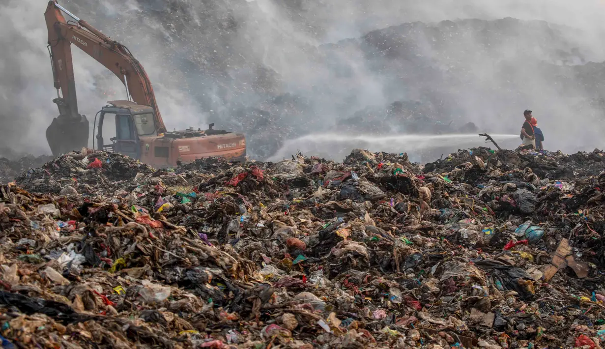 Petugas pemadam kebakaran dan alat berat  berusaha memadamkan api di Tempat Pembuangan Akhir (TPA) Jatiwaringin, Kabupaten Tangerang, Banten, Jumat (03/07/2026). (Merdeka.com/ Arie Basuki)