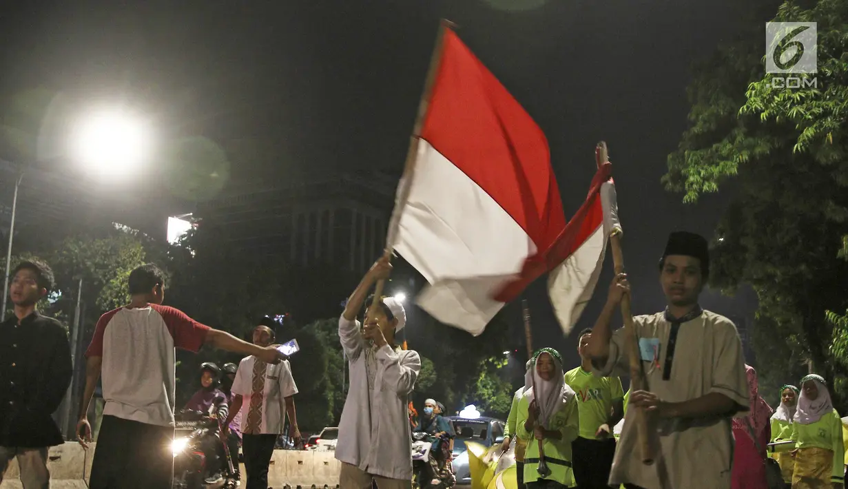 Anak-anak mengibarkan bendera merah ptih saat pawai obor di kawasan Mampang Prapatan, Jakarta, Sabtu (12/5). Pawai obor berkeliling dari Pejatan sampai Warung Buncit menyambut Ramadan 1439 H. (Liputan6.com/Herman Zakharia)