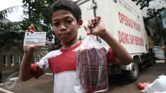 Seorang anak memperlihatkan daging beku yang baru dibeli pada operasi pasar murah di Kantor Kecamatan Matraman, Jakarta, Senin (27/6). Operasi pasar ini menjual daging sapi & ayam murah kepada pemegang KJP Sekolah Dasar (SD). (Liputan6.com/Faizal Fanani)