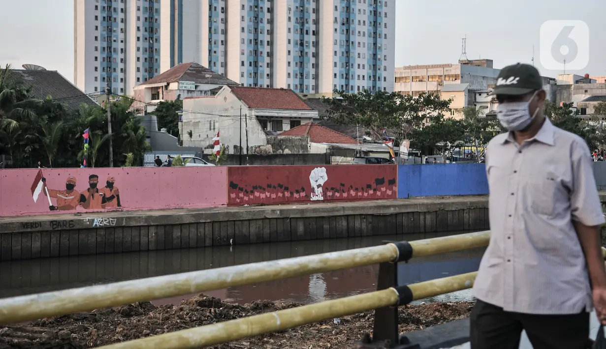 Warga melintasi mural bertema HUT ke-75 RI yang menghiasi jalan di Kampung Melayu, Jakarta, Minggu (16/8/2020). Jelang HUT ke-75 RI, mural bernuansa Merah Putih banyak menghiasi jalanan Ibu Kota guna memberi semangat nasionalisme kepada warga di tengah pandemi COVID-19. (merdeka.com/Iqbal S.Nugroho)