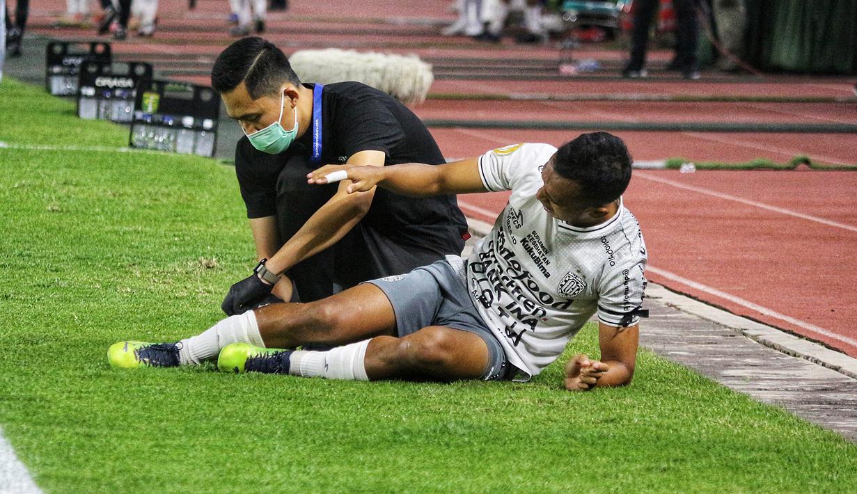 Irfan Jaya pun kesakitan dipinggir lapangan dan langsung mendapatkan perawatan dari tim medis Bali United. (Bola.com/Wahyu Pratama)