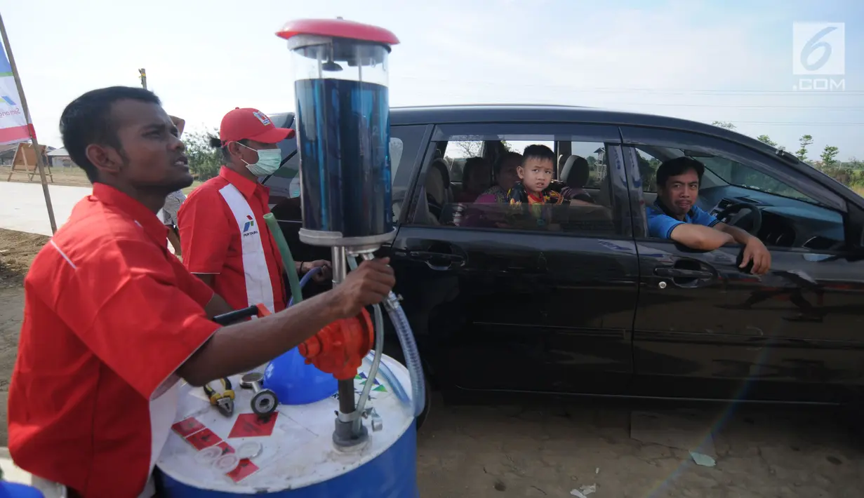 Petugas mengisi bahan bakar minyak (BBM) ke sebuah mobil pemudik di kios Pertamina jalan tol fungsional Brebes Timur-pemalang Km 275, Kabupaten Tegal, Jawa Tengah, Rabu (21/6). (Liputan6.com/Gempur M Surya)