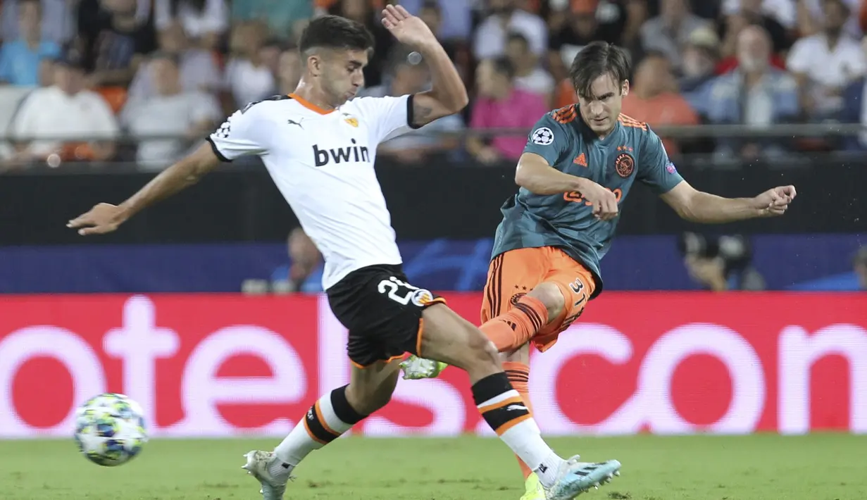 Pemain Ajax Amsterdam, Nicolas Tagliafico berusaha mengumpan bola dari kawalan pemain Valencia, Ferran Torres pada lanjutan pertandingan grup H Liga Champions di stadion Mestalla, Spanyol (2/10/2019). Ajax menang telak 3-0 atas Valencia. (AP Photo/Alberto Saiz)