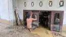 Meski, di sejumlah lokasi air mulai surut, ketinggian material sisa banjir menimbun sejumlah rumah warga hingga nyaris menyentuh bagian atap. Tampak dalam foto, seorang warga membersihkan lumpur tebal dari pintu masuk rumahnya yang terendam banjir bandang di Meureudu, Kabupaten Pidie Jaya, Provinsi Aceh, Jumat 28 November 2025. (CHAIDEER MAHYUDDIN/AFP)