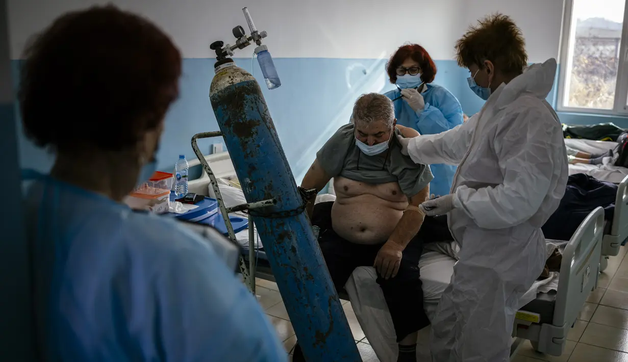 Spesialis penyakit Infeksi Bulgaria Dr Maria Bogoeva (kiri) mengamati rekan kerja memeriksa pasien di unit Covid-19 di sebuah rumah sakit kecil di Bulgaria pada 20 Januari 2021. Perempuan berusia 82 tahun itu siap untuk pensiun dari jabatannya ketika pandemi virus corona melanda. (Dimitar DILKOFF/AF