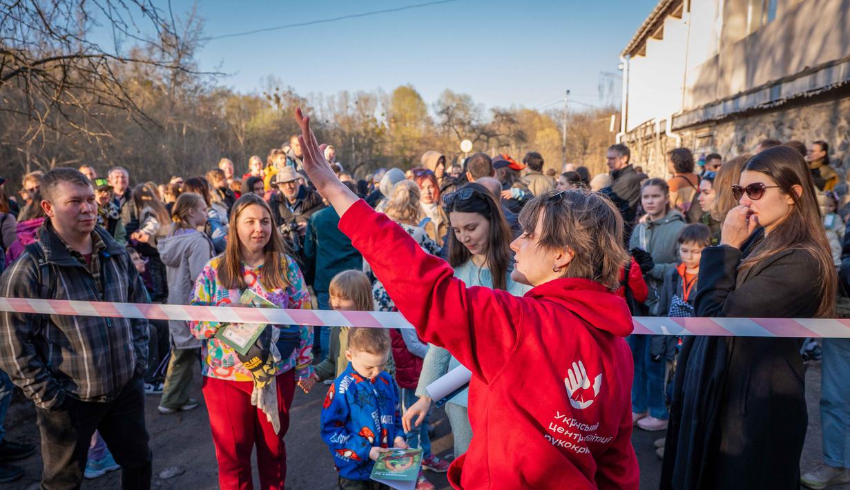 Sebagai informasi, Ukrainian Bat Rehabilitation Center merupakan pusat rehabilitasi kelelawar terbesar di Eropa Timur. Tampak dalam foto, seorang sukarelawan dari pusat rehabilitasi kelelawar Ukraina memberi isyarat kepada orang-orang sebelum upacara pengembalian kelelawar ke alam liar di Kyiv, Ukraina, Sabtu, 4 April 2026. (AP Photo/Dan Bashakov)