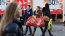 Dua wanita berjalan membawa kantong belanjaan selama Boxing Day di Liverpool, Inggris, Selasa (26/12). Pada Boxing Day, hampir semua pusat pertokoan yang memberikan pesta diskon diserbu para pembeli dan terjadi antrean panjang. (Peter Byrne/PA via AP)