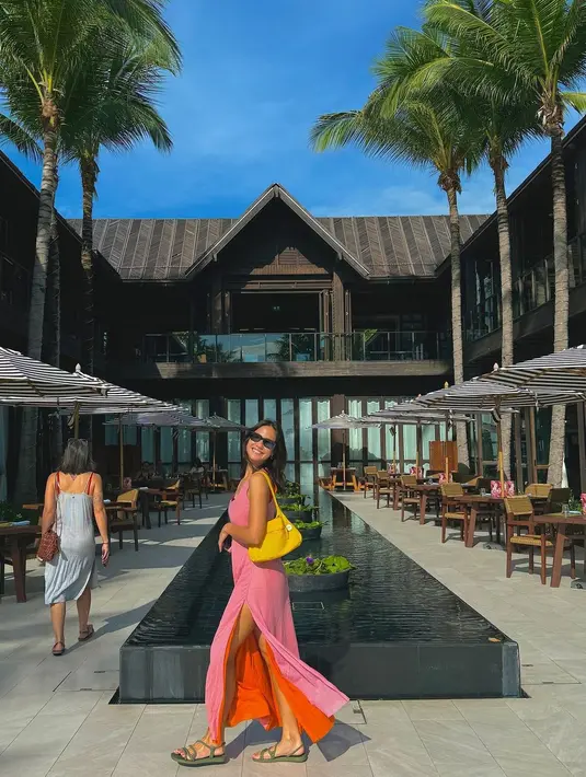 Pevita Pearce pakai dress two-tone pink dan oranye tanpa lengan, ia padukan gaya summernya ini dengan tas kuning dan sandal hijau, serta sunglasses. [Foto: Instagram/pevpearce]
