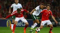 Gelandang Irlandia, David Meyler, berusaha melewati gelandang Wales, Aaron Ramsey, pada laga kualifikasi Piala Dunia 2018 di Stadion Cardiff City, Cardiff, Senin (9/10/2017). Wales kalah 0-1 dari Irlandia. (AFP/Geoff Caddick)