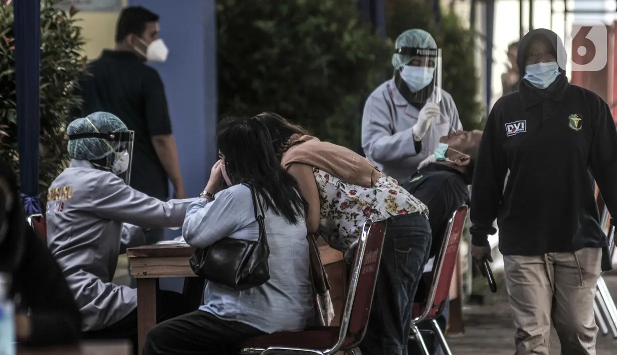 Tenaga kesehatan melakukan tes usap COVID-19 kepada keluarga korban pesawat Sriwijaya Air SJ 182 sebelum memberikan data di Posko Ante Mortem DVI, RS Polri, Jakarta, Minggu (10/1/2020). Keluarga mendatangi posko untuk memberikan Informasi data primer dan sekunder. (merdeka.com/Iqbal S. Nugroho)