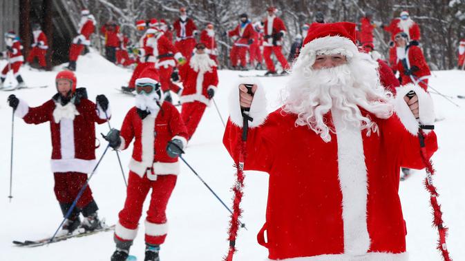 Pemain ski dan snowboarder berpakaian Santa Claus menuruni lereng gunung saat Santa Sunday ke-19 di Newry, Maine, AS, Minggu (2/12). Peserta harus menyumbang 20 US dolar untuk mendukung program pendidikan dan rekreasi setempat. (AP Photo/Robert F. Bukaty)